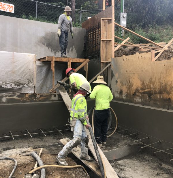 Construction workers pouring concrete at site.