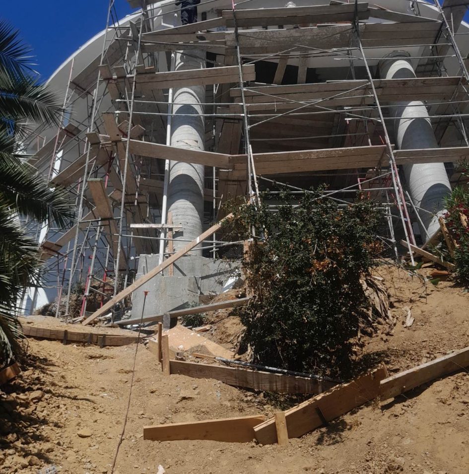 Building under construction with scaffolding and beams.